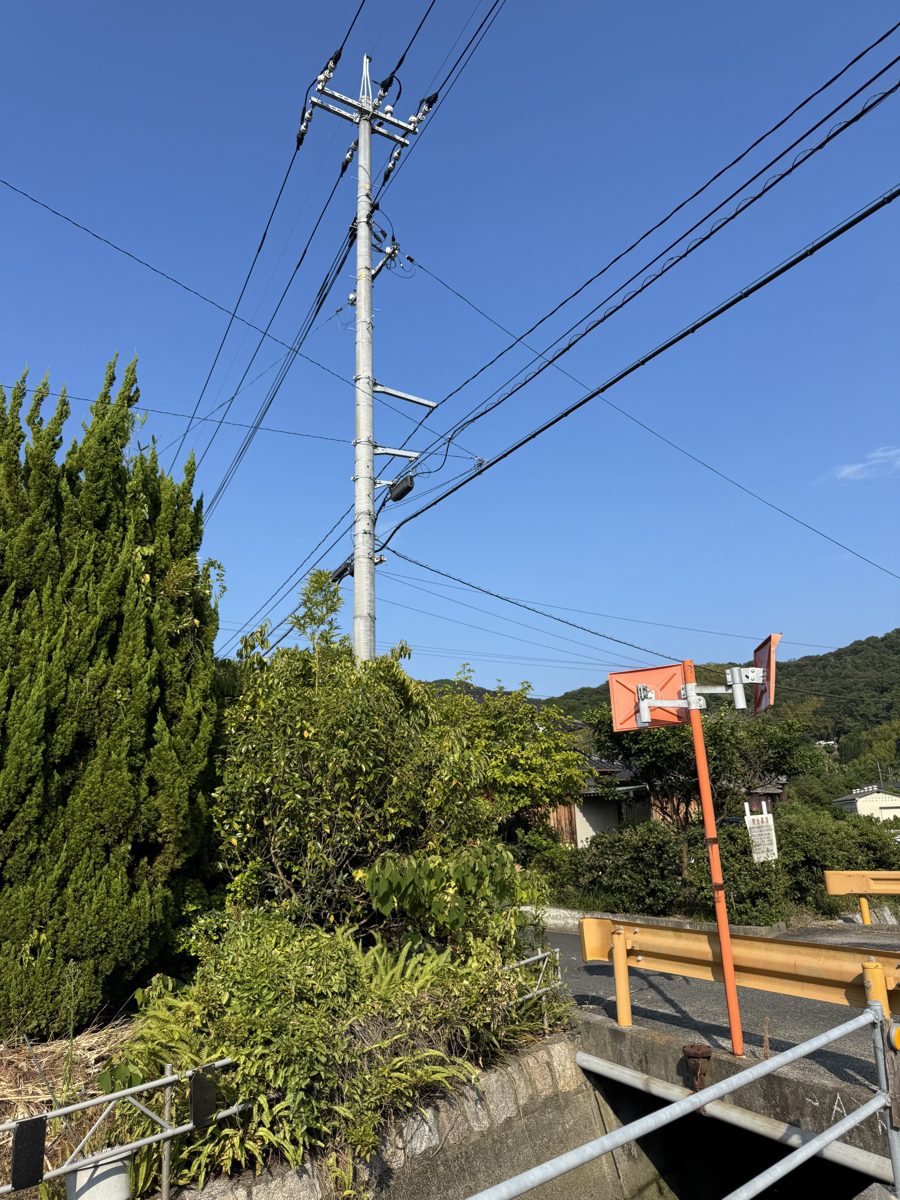 腕金が2段付いた電柱を見上げた写真。それぞれの腕金の上にがいしが並んで電線を支え、低い位置には通信線も通っている